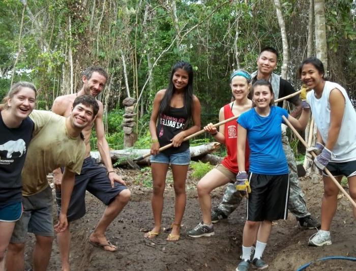 八名圣玛丽的学生以巴西热带雨林的树木为背景摆姿势拍照